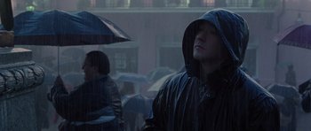Movie still from “Runaway Jury” (2003), directed by Gary Fleder – A man in a raincoat and holding an umbrella in the rain; Close Up shot, Low angle