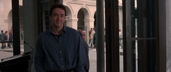 Movie still from “Runaway Jury” (2003), directed by Gary Fleder – A man standing in front of a group of people on a street; Medium shot, Over the shoulder angle