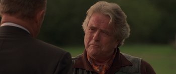 Movie still from “Runaway Jury” (2003), directed by Gary Fleder – An older man with grey hair is looking at the camera; Close Up shot, Over the shoulder angle