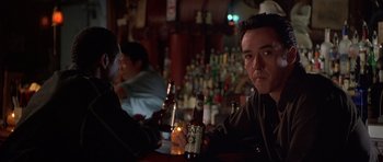 Movie still from “Runaway Jury” (2003), directed by Gary Fleder – A man sitting at a table with a bottle of beer in front of him; Close Up shot, Over the shoulder angle