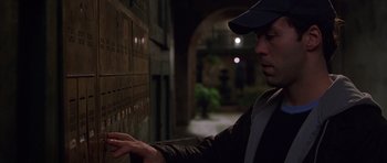 Movie still from “Runaway Jury” (2003), directed by Gary Fleder – A man in a baseball cap is looking at a wall of mail; Medium shot, Low angle