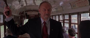 Movie still from “Runaway Jury” (2003), directed by Gary Fleder – An older man wearing a suit and tie on a train; Close Up shot, Low angle