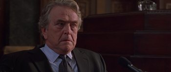 Movie still from “Runaway Jury” (2003), directed by Gary Fleder – An older man wearing a suit and tie looking at the camera; Close Up shot, Low angle