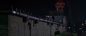 Movie still from “Runaway Jury” (2003), directed by Gary Fleder – A man standing on a fence at night; Extreme Wide shot, Low angle
