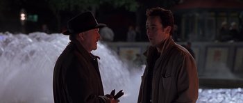 Movie still from “Runaway Jury” (2003), directed by Gary Fleder – Two men are talking in front of a fountain; Medium shot, Over the shoulder angle