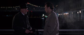 Movie still from “Runaway Jury” (2003), directed by Gary Fleder – Two men standing next to each other near a body of water at night; Medium shot, Over the shoulder angle