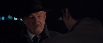 Movie still from “Runaway Jury” (2003), directed by Gary Fleder – An older man wearing a black hat and a black coat; Close Up shot, Over the shoulder angle