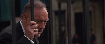 Movie still from “Runaway Jury” (2003), directed by Gary Fleder – An older man in a suit talking on a cell phone behind bars; Close Up shot, Low angle