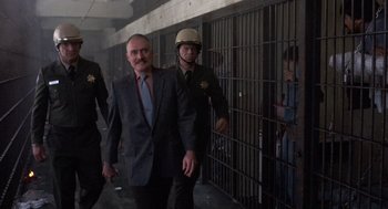 Movie still from “Runaway Train” (1985), directed by Andrey Konchalovskiy – A man in a suit and tie next to a man in a jail cell; Medium shot, Over the shoulder angle