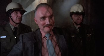 Movie still from “Runaway Train” (1985), directed by Andrey Konchalovskiy – A man in a suit and tie with a mustache; Close Up shot, Over the shoulder angle