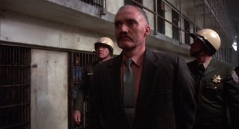 Movie still from “Runaway Train” (1985), directed by Andrey Konchalovskiy – A man in a suit standing next to another man in a prison cell; Close Up shot, Over the shoulder angle