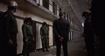 Movie still from “Runaway Train” (1985), directed by Andrey Konchalovskiy – A group of men standing next to each other in front of a building; Wide shot, Over the shoulder angle