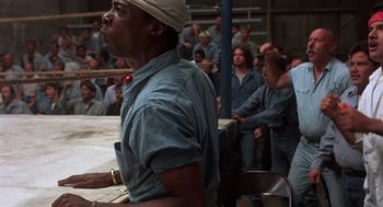 Movie still from “Runaway Train” (1985), directed by Andrey Konchalovskiy – A man with a white head band is in the middle of a crowd; Medium shot, Low angle