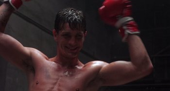 Movie still from “Runaway Train” (1985), directed by Andrey Konchalovskiy – A shirtless man in a boxing ring holding a red glove; Close Up shot, Low angle