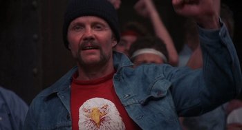 Movie still from “Runaway Train” (1985), directed by Andrey Konchalovskiy – A man with a bald head wearing a denim jacket; Medium shot, Low angle