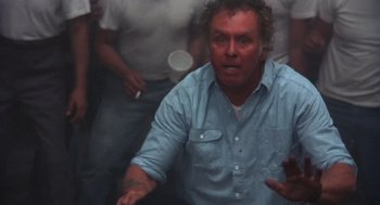 Movie still from “Runaway Train” (1985), directed by Andrey Konchalovskiy – A man in a blue shirt is holding his hands out; Close Up shot, High angle