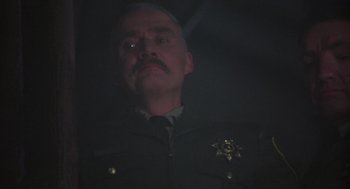 Movie still from “Runaway Train” (1985), directed by Andrey Konchalovskiy – A man in a police uniform is looking at the camera; Close Up shot, Low angle