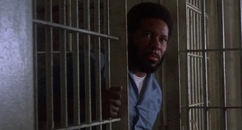 Movie still from “Runaway Train” (1985), directed by Andrey Konchalovskiy – A man standing behind bars in a jail cell; Close Up shot, High angle