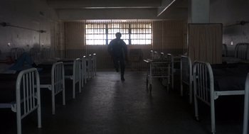 Movie still from “Runaway Train” (1985), directed by Andrey Konchalovskiy – A person walking in a room with chairs and tables; Wide shot, Low angle