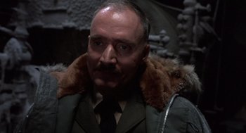 Movie still from “Runaway Train” (1985), directed by Andrey Konchalovskiy – An older man with a mustache wearing a coat and tie; Close Up shot, Low angle