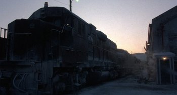 Movie still from “Runaway Train” (1985), directed by Andrey Konchalovskiy – An old train sitting on the train tracks at dusk; Extreme Wide shot, Low angle