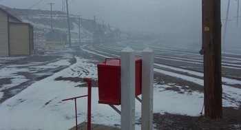 Movie still from “Runaway Train” (1985), directed by Andrey Konchalovskiy – A red box sitting on the side of a road in the snow; Extreme Wide shot, High angle