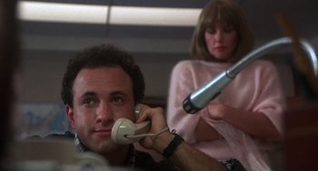 Movie still from “Runaway Train” (1985), directed by Andrey Konchalovskiy – A man on the phone while a woman in a pink dress looks at him; Close Up shot, Low angle
