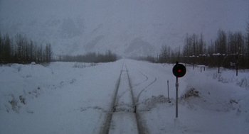 Movie still from “Runaway Train” (1985), directed by Andrey Konchalovskiy – A train track in the middle of a snow covered field; Extreme Wide shot, High angle