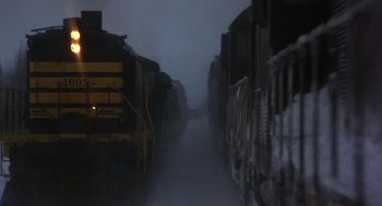Movie still from “Runaway Train” (1985), directed by Andrey Konchalovskiy – A train traveling down train tracks on a foggy day; Extreme Wide shot, Low angle