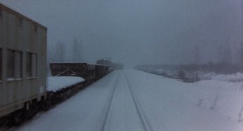 Movie still from “Runaway Train” (1985), directed by Andrey Konchalovskiy – A train traveling down train tracks in the snow; Extreme Wide shot, High angle