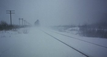 Movie still from “Runaway Train” (1985), directed by Andrey Konchalovskiy – A train traveling down train tracks through a snow covered field; Extreme Wide shot, High angle