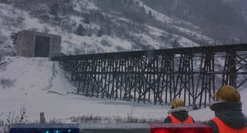 Movie still from “Runaway Train” (1985), directed by Andrey Konchalovskiy – A person in a red vest standing in front of a snow covered bridge; Extreme Wide shot, Low angle