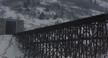 Movie still from “Runaway Train” (1985), directed by Andrey Konchalovskiy – A wooden bridge in the middle of a snow covered forest; Extreme Wide shot, Low angle