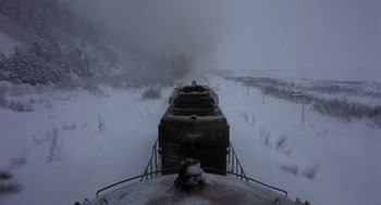 Movie still from “Runaway Train” (1985), directed by Andrey Konchalovskiy – A steam train traveling through a snowy landscape; Extreme Wide shot, High angle