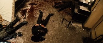 Movie still from “Running Scared” (2006), directed by Wayne Kramer – A man in a black suit lying on the ground; Wide shot, Overhead angle