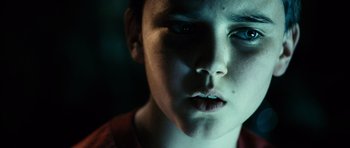 Movie still from “Running Scared” (2006), directed by Wayne Kramer – A young boy with a blue eye stares into the camera; Close Up shot, Low angle