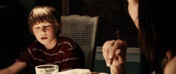 Movie still from “Running Scared” (2006), directed by Wayne Kramer – Two people sitting at a table with a glass of water; Close Up shot, Over the shoulder angle