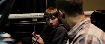 Movie still from “Running Scared” (2006), directed by Wayne Kramer – A man holding a cell phone while sitting next to a woman; Close Up shot, Over the shoulder angle
