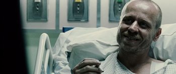Movie still from “Running Scared” (2006), directed by Wayne Kramer – An older man in a hospital bed with his hand up to his mouth; Close Up shot, Overhead angle