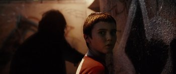 Movie still from “Running Scared” (2006), directed by Wayne Kramer – A young boy standing next to a stone wall; Close Up shot, Over the shoulder angle