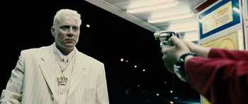 Movie still from “Running Scared” (2006), directed by Wayne Kramer – A person taking a picture of a man in a white suit; Close Up shot, Over the shoulder angle