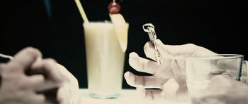 Movie still from “Running Scared” (2006), directed by Wayne Kramer – A hand holding a key in front of a glass of milk; Extreme Close Up shot, High angle