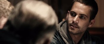 Movie still from “Running Scared” (2006), directed by Wayne Kramer – A person sitting down; Close Up shot, Over the shoulder angle