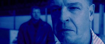 Movie still from “Running Scared” (2006), directed by Wayne Kramer – A man with a beard is looking at the camera; Close Up shot, Low angle