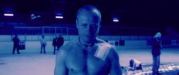Movie still from “Running Scared” (2006), directed by Wayne Kramer – A man with a bandage on his shoulder; Medium shot, Low angle