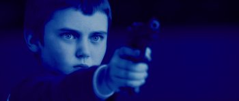Movie still from “Running Scared” (2006), directed by Wayne Kramer – A young man holding a gun in a dark room; Close Up shot, High angle