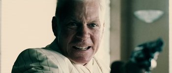 Movie still from “Running Scared” (2006), directed by Wayne Kramer – An older man with white hair and wearing a white shirt; Close Up shot, Low angle