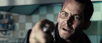 Movie still from “Running Scared” (2006), directed by Wayne Kramer – A person holding a gun in a room; Close Up shot, Over the shoulder angle