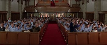 Movie still from “Rushmore” (1998), directed by Wes Anderson – A group of people sitting in pews in a church; Extreme Wide shot, Low angle