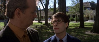 Movie still from “Rushmore” (1998), directed by Wes Anderson – A man wearing glasses and a suit talks to another man; Close Up shot, Over the shoulder angle
